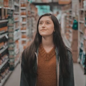 A thoughtful woman browsing aisles in a grocery store.