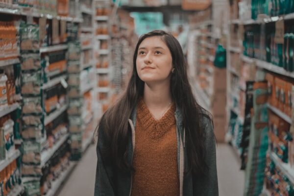 A thoughtful woman browsing aisles in a grocery store.