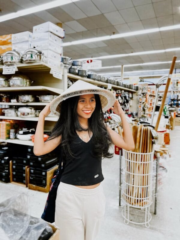 Smiling woman wearing a conical hat in a Dallas supermarket, enjoying shopping.